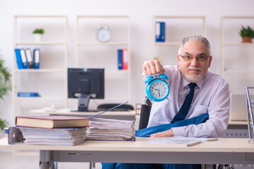 Old male employee in wheel-chair in time management concept