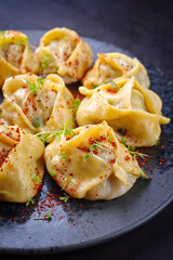 Traditional steamed Kazakh manti garnished with mincemeat and sumah served as close-up on a Nordic design plate