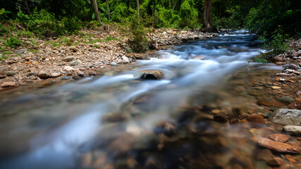 Obraz premium majestic deep waterfall flowing motion in rainforest with sunlight, panoramic wilderness and wet heaven freshness in the morning, hiking into the wild natural forest