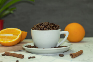White coffee cup with coffee beans and cinnamon sticks