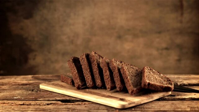 Super slow motion on the cutting board fall pieces of bread. Against a dark background. Filmed on a high-speed camera at 1000 fps.