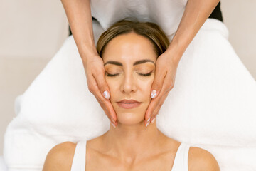 Middle-aged woman having a head massage in a beauty salon.