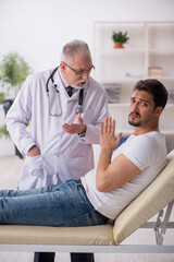 Obraz premium Young male patient visiting old male doctor