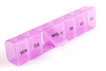Pink plastic organizer, for pills isolated on white background. Close up on compartments pill case with clip lids medicine. Daily vitamins and supplements dosage routine concept. Full depth of field.