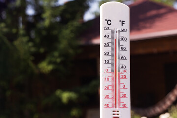 Thermometer on the background of a country house. An air temperature of 40 degrees is shown by a thermometer. Summer heat