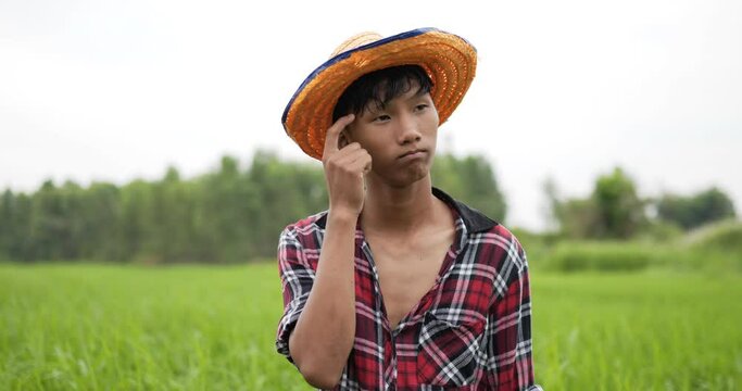 Young farmer use fingers to tap temples while thinking.