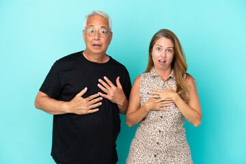 Middle age couple isolated on blue background surprised and shocked while looking right