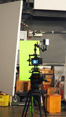 Video Camera set up on tripod and professional camera cage rig. Behind video DSLR camera and green screen background for chroma key technique. 
