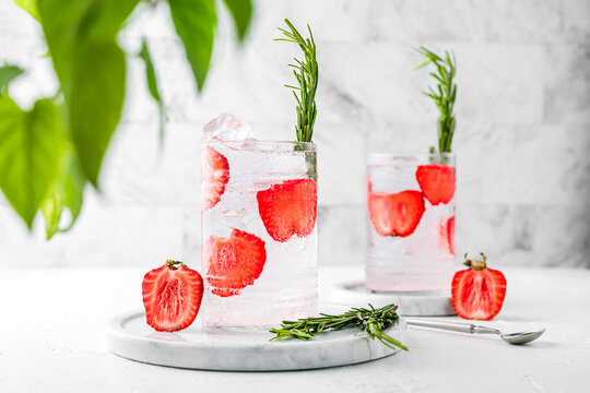 Two highball collins glasses of refreshing strawberry rosemary sparkling lemonade. Light and bright horizontal image.