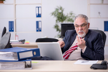 Old male employee sitting at workplace