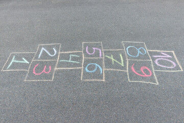 Close-up photo of chalk painted hopscotch on asphalt. School yard. Back to school. - obrazy, fototapety, plakaty