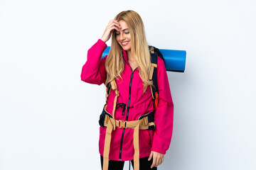 Young mountaineer woman with a big backpack over isolated white background laughing