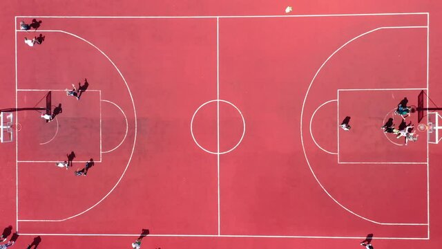 Aerial view of young athletes playing street basketball on an open summer playground. Sports teams compete in a basketball match in the same ring.
