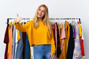 Young Uruguayan blonde woman in a clothing store giving a thumbs up gesture