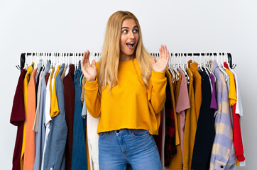 Young Uruguayan blonde woman in a clothing store with surprise facial expression