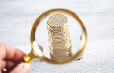 Male hand magnifying coins. Inspect income