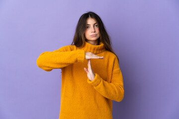 Young caucasian woman isolated on purple background making time out gesture