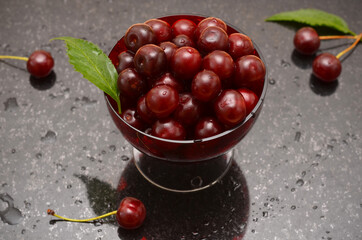 ripe cherries in a bowl on a black marble background