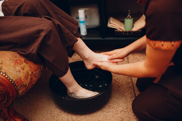 Thai man washing feet legs and making classical thai massage procedure to young woman at beauty spa...