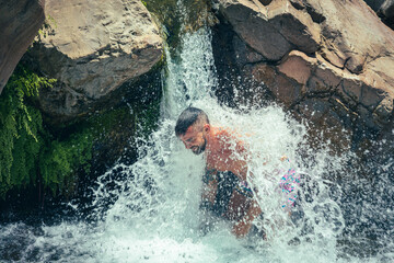 man bathing in waterfall