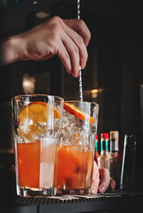 bartender hand mixing cocktail Lemonade with ice cubes in glass to customers at bar 