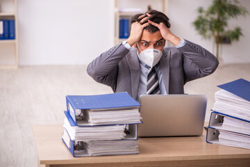 Young male employee working at workplace during pandemic