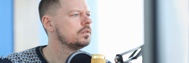 Obraz premium Young man sitting in front of microphone in recording studio