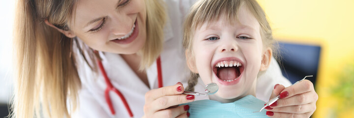 Dentist examines teeth of smiling girl closeup