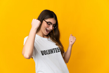 Young volunteer woman isolated on yellow background celebrating a victory