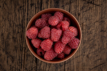 red fresh domestic raspberry at bowl on a rustic table top. space