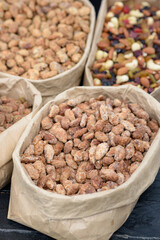 Almonds and pistachios with spices lie in paper bags on the counter.