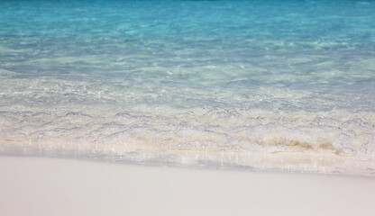 Fototapeta na wymiar Blue ocean waves on sandy beach. Background image of waves of blue ocean on white sandy beach. Ocean wave closeup.