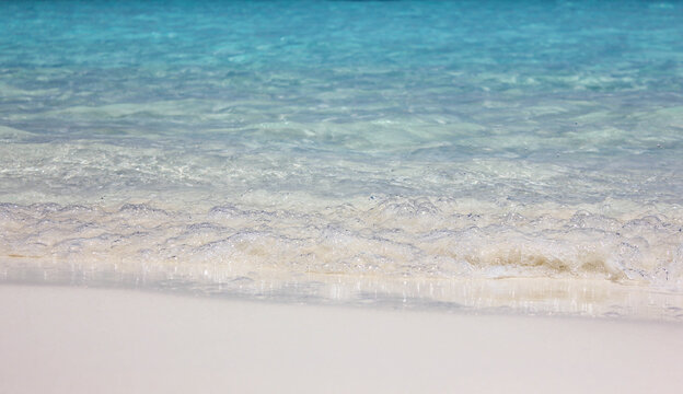 Blue ocean waves on sandy beach. Background image of waves of blue ocean on white sandy beach. Ocean wave closeup.