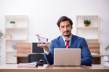 Young male employee in e-commerce concept at workplace