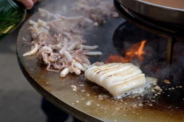 Octopus meat is prepared at the street food festival with smoke and fire.