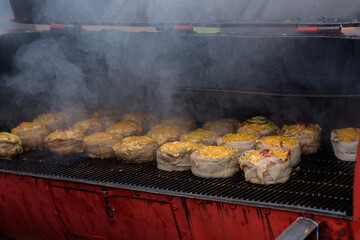 Handmade hamburger patties during the street food festival, smoke while cooking.