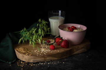 fresh and healthy breakfast made of fruits and oatmeal on a rustic wooden plate with black background, dark and moody food photography