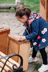 child girl helps parents polish an old wooden chest of drawers for repair and reuse against the background of a green garden, family hobby.  - obrazy, fototapety, plakaty