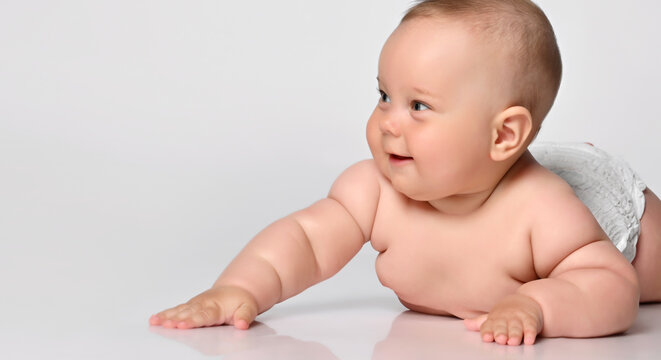 portrait Six month old baby girl in a diaper, lying down and looking with interest to the side, arms outstretched to the sides. on white background