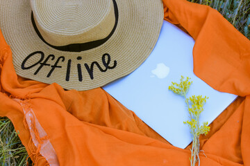 A straw hat with a written word Offline. An orange rag background, a gray laptop flatly. Lack of...