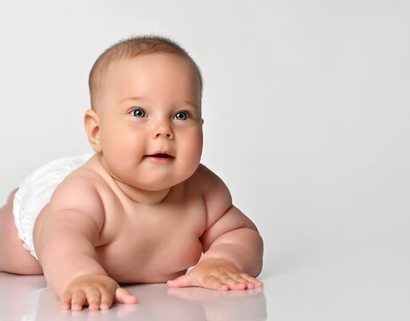 portrait of a baby in a diaper, he lies naked on his stomach, and looks up with interest.