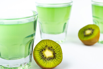 Sweet dessert, kiwi jelly in glass glasses and next to fresh kiwi, cut into two halves on a white background