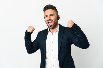 Telemarketer man working with a headset isolated on white background celebrating a victory