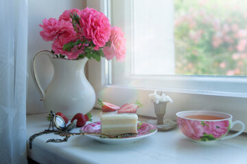 Fototapeta na wymiar Still life of cake with strawberries, a cup of tea and a beautiful bouquet on the window.