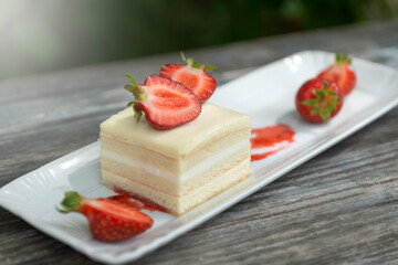 Cake with cream and strawberries on a dark wood background.