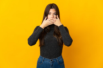 Teenager Brazilian girl isolated on yellow background covering mouth with hands