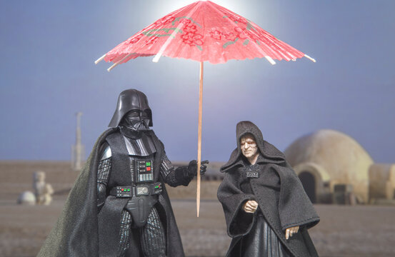 NEW YORK, USA - JUNE 12 2021: Humor image, Star Wars Sith Lord Darth Vader and Emperor Palpatine on Tatooine with sun umbrella - Hasbro action figure