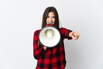 Teenager Brazilian girl isolated on white background shouting through a megaphone to announce...