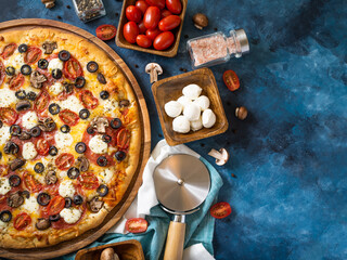 Pizza and there are many ingredients around - tomatoes, mushrooms, as well as a pizza knife....