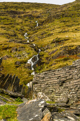 Hillside with stream and old slate wall.